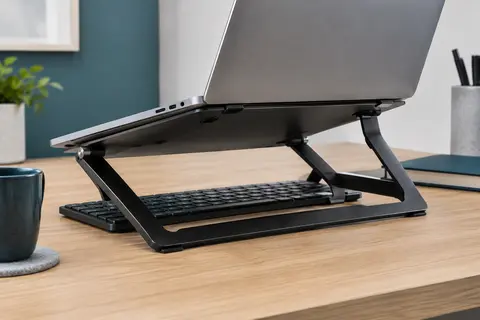 Support Besign LSX6N en aluminium noir sous un ordinateur portable, posé sur un bureau clair.